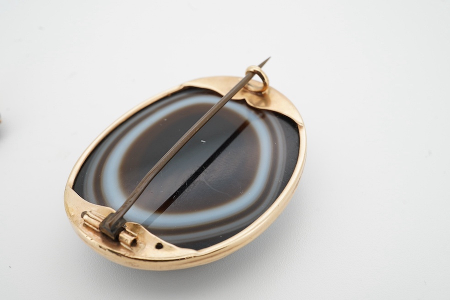 A yellow metal mounted banded agate oval brooch, 41mm, together with a yellow metal and banded agate set bar brooch. Condition - fair to good